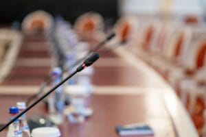 Microphone on a conference table with blurred chairs and water bottles in the background